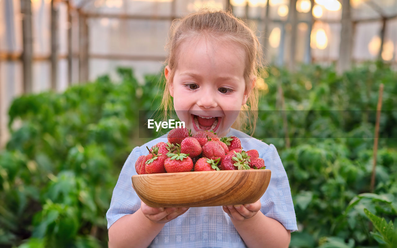 portrait of cute baby boy holding strawberries