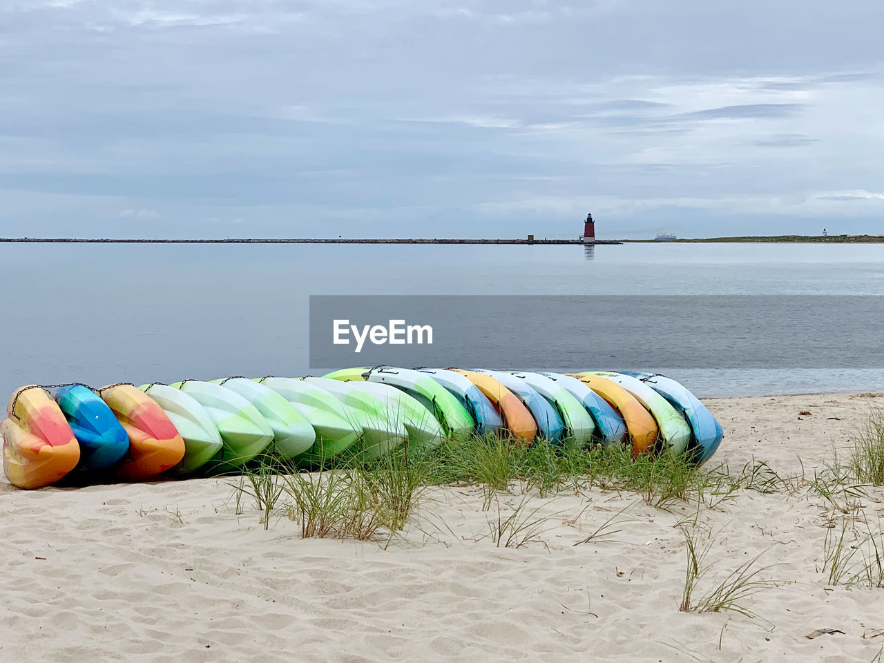 Multi colored kayaks on beach against sky