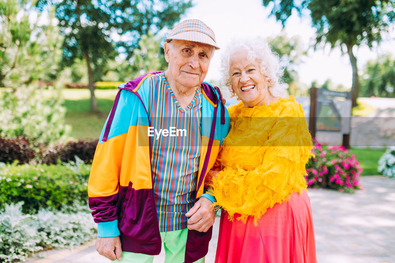 portrait of smiling couple standing against trees