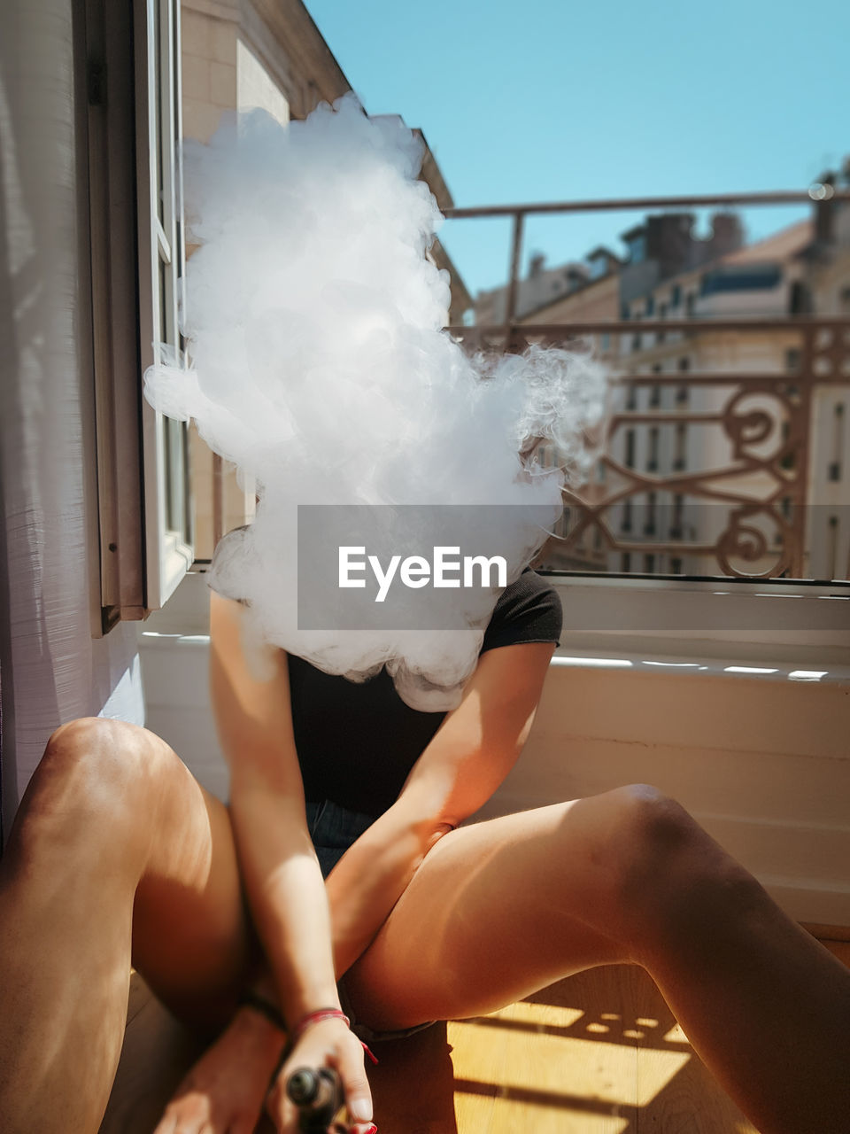 Woman exhaling smoke while sitting in balcony