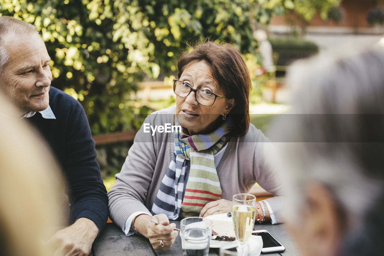 Senior woman talking with friends at cafe table