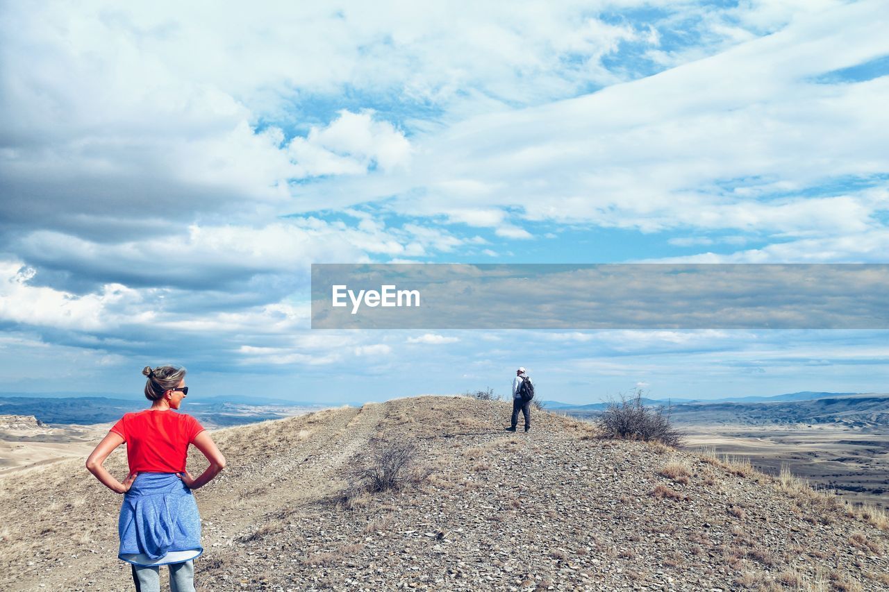 REAR VIEW OF MAN AND WOMAN STANDING ON ROAD