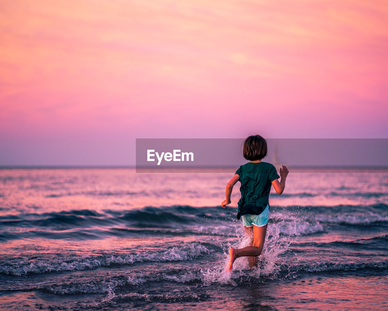 REAR VIEW OF GIRL ON BEACH AGAINST SKY