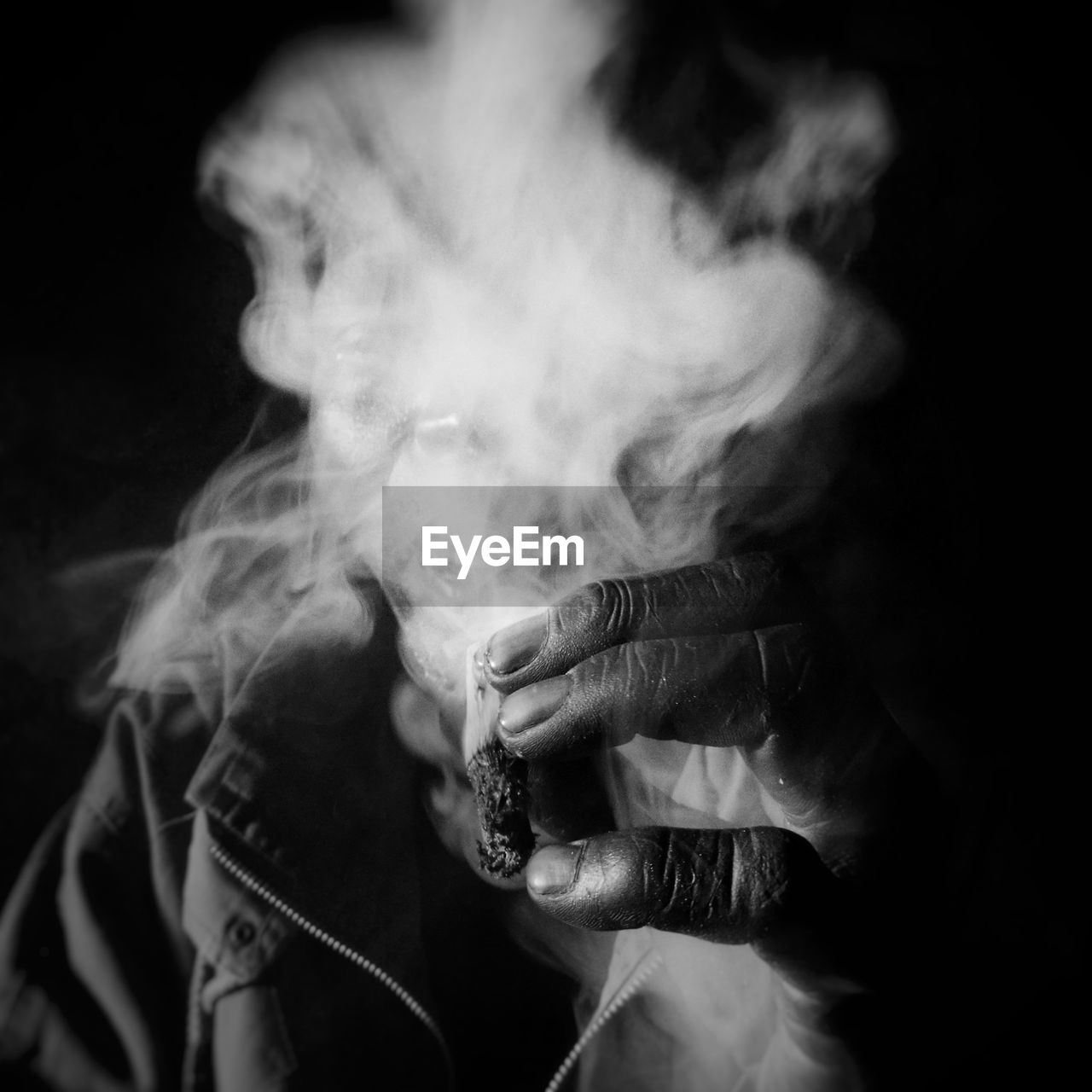 Close-up of man smoking over black background