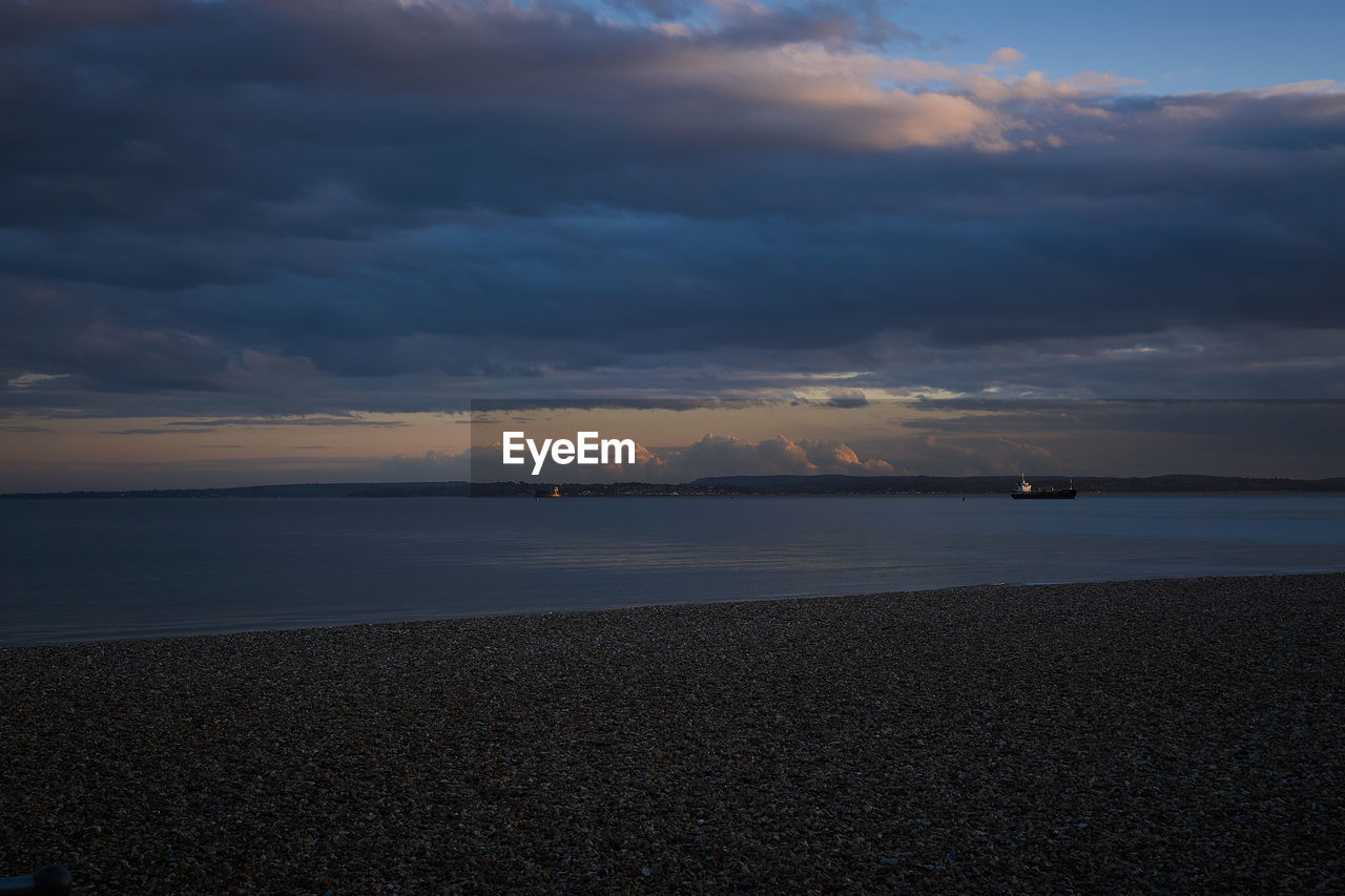 Scenic view of sea against dramatic sky at sunset