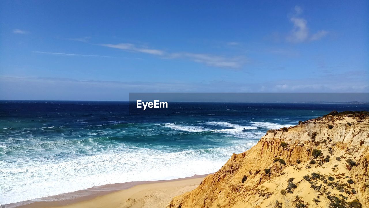 Scenic view of beach and mountain against blue sky