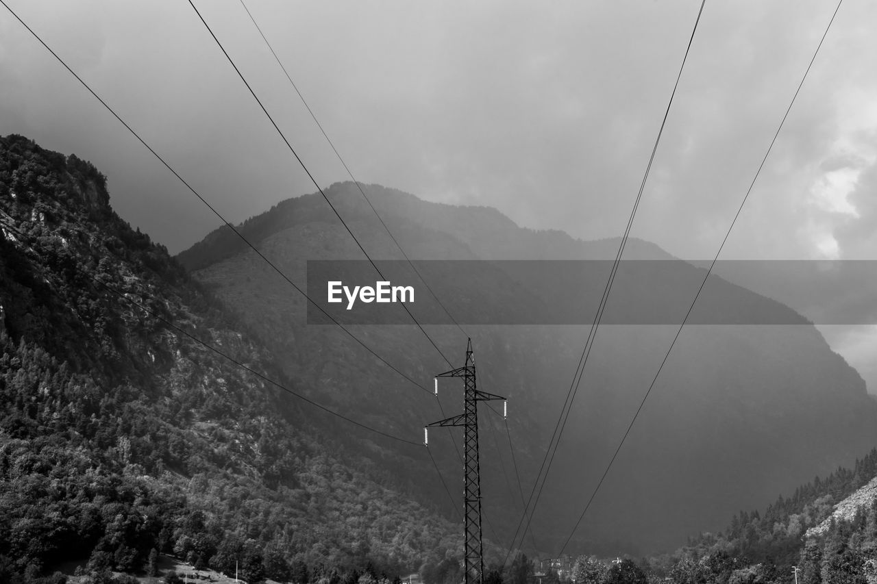 Overhead cable car over mountains against sky