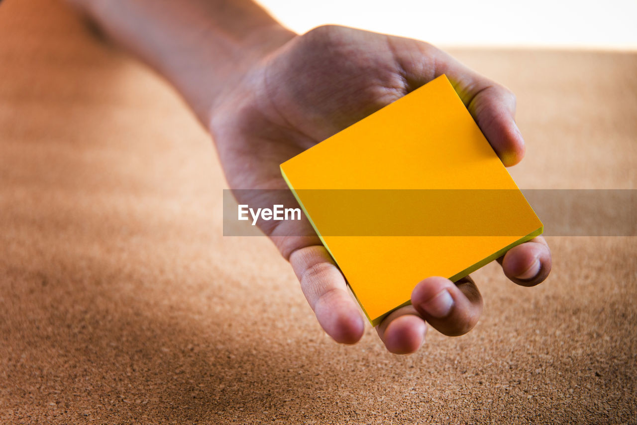 Close-up of person holding orange paper