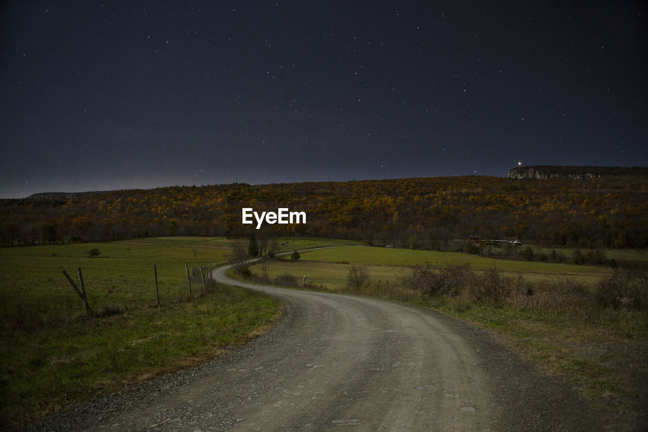 Road amidst field against sky at night