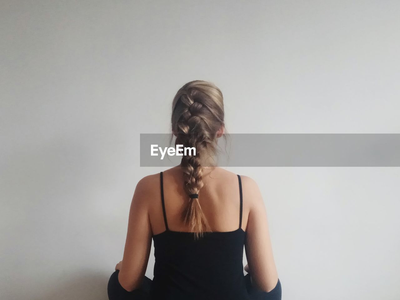 Woman with braided hair standing against wall