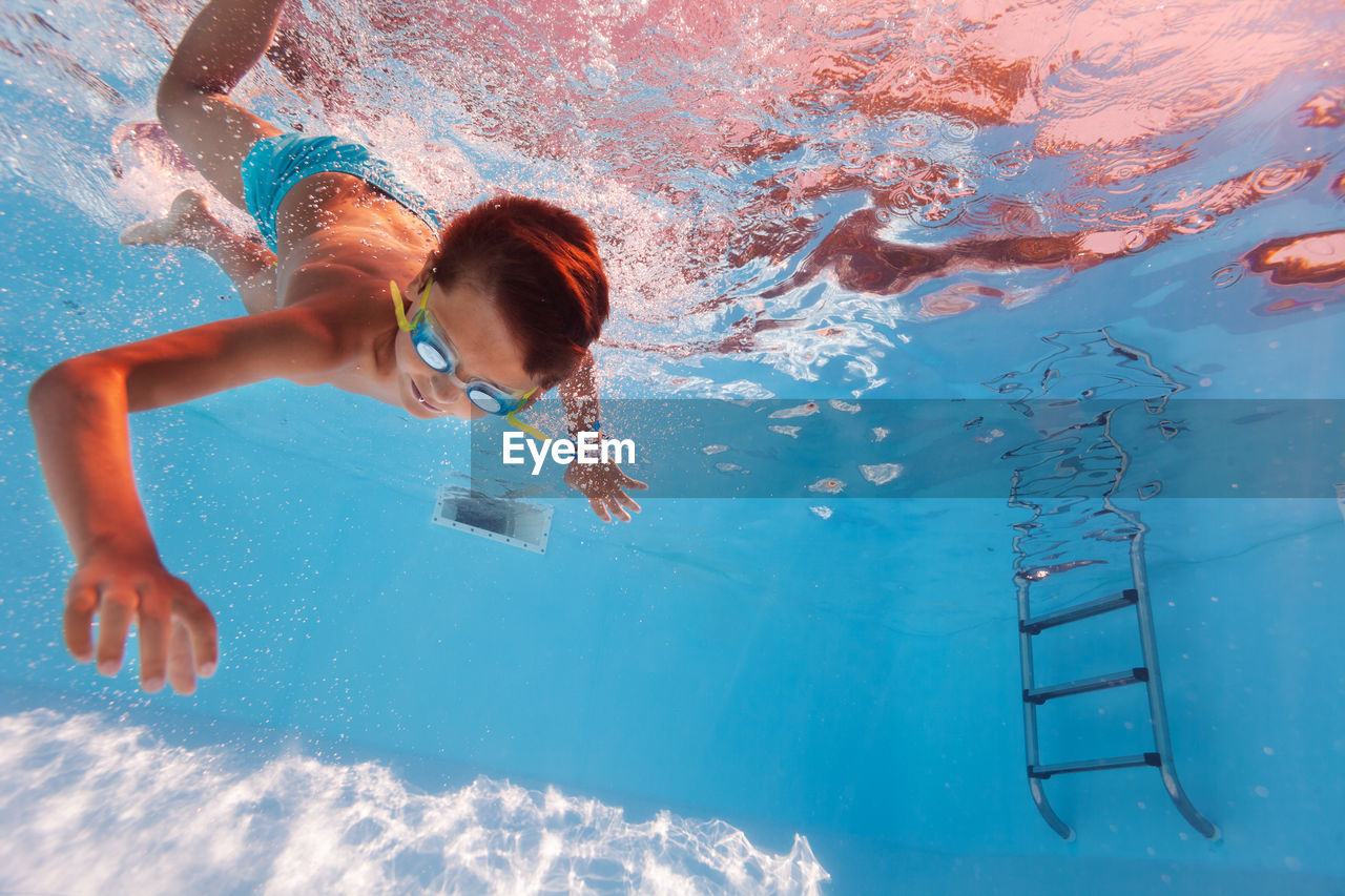 high angle view of shirtless boy swimming in pool