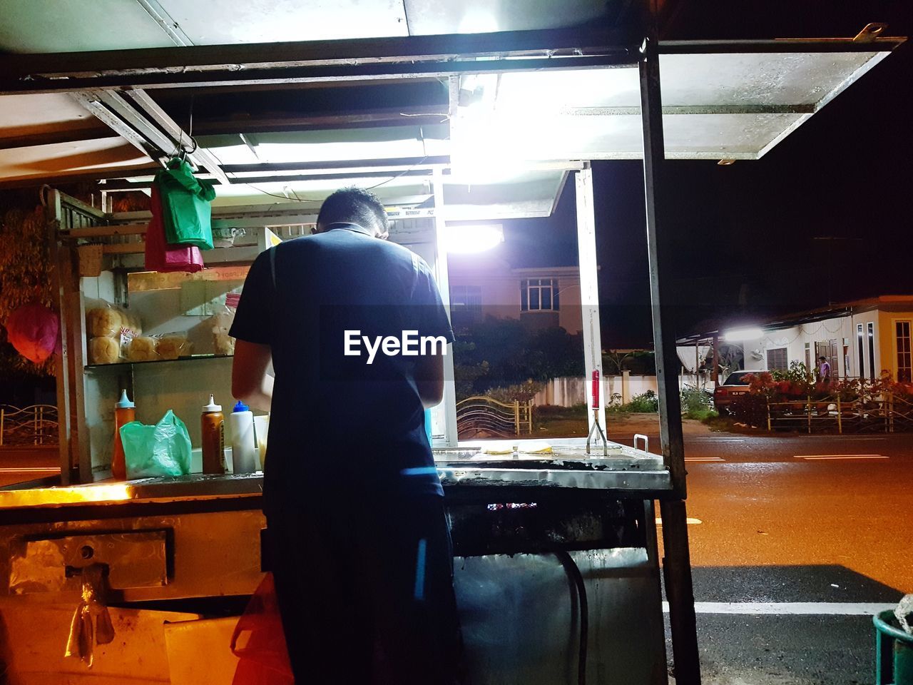 REAR VIEW OF MAN STANDING IN ILLUMINATED UNDERGROUND