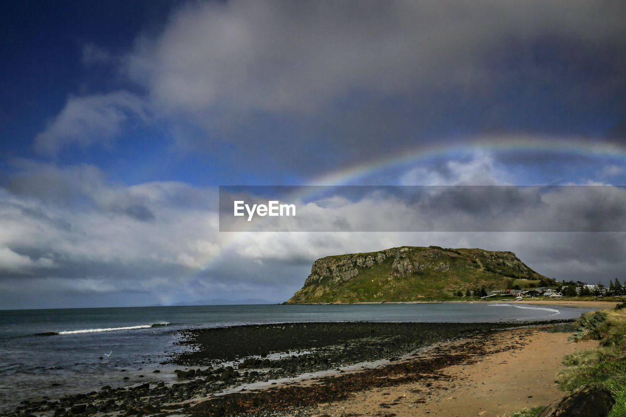 Scenic view of sea against rainbow in sky