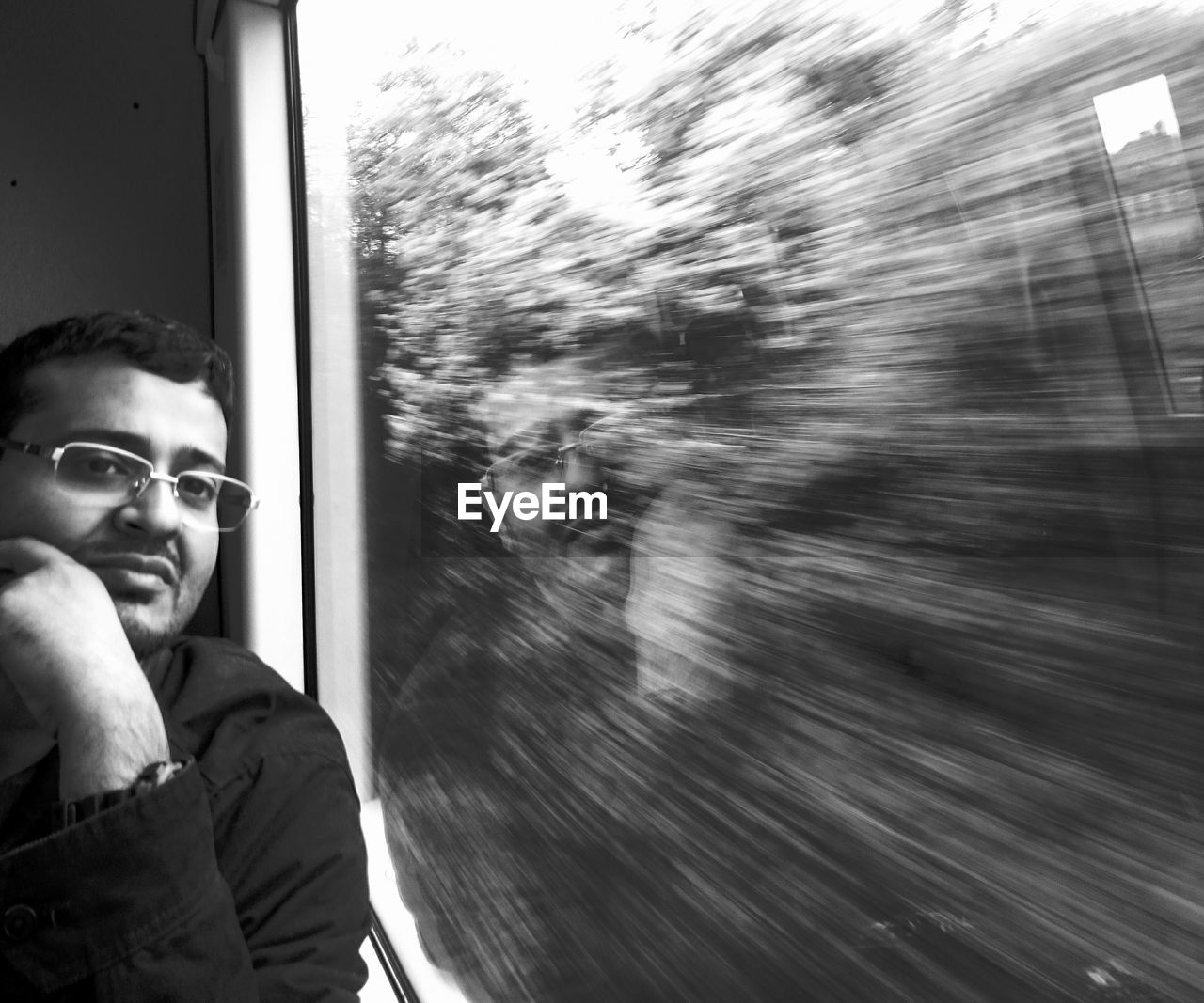 Man reflecting on window while traveling in train