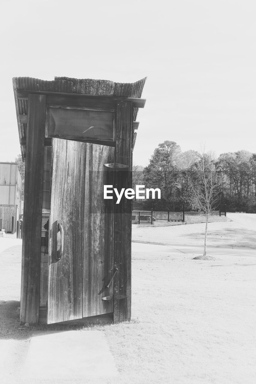 Wooden doorway by grassy field against sky