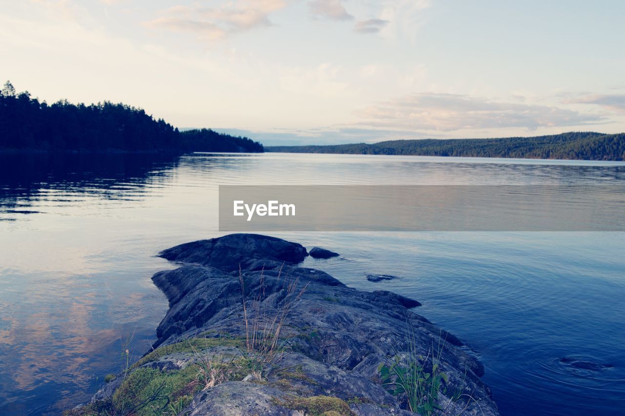 SCENIC VIEW OF ROCKS BY LAKE AGAINST SKY