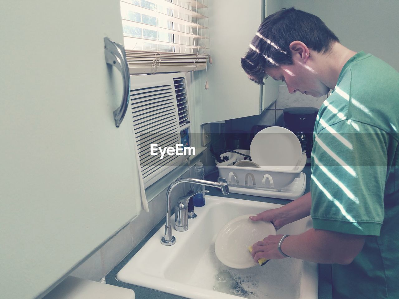 Woman washing dishes at kitchen sink