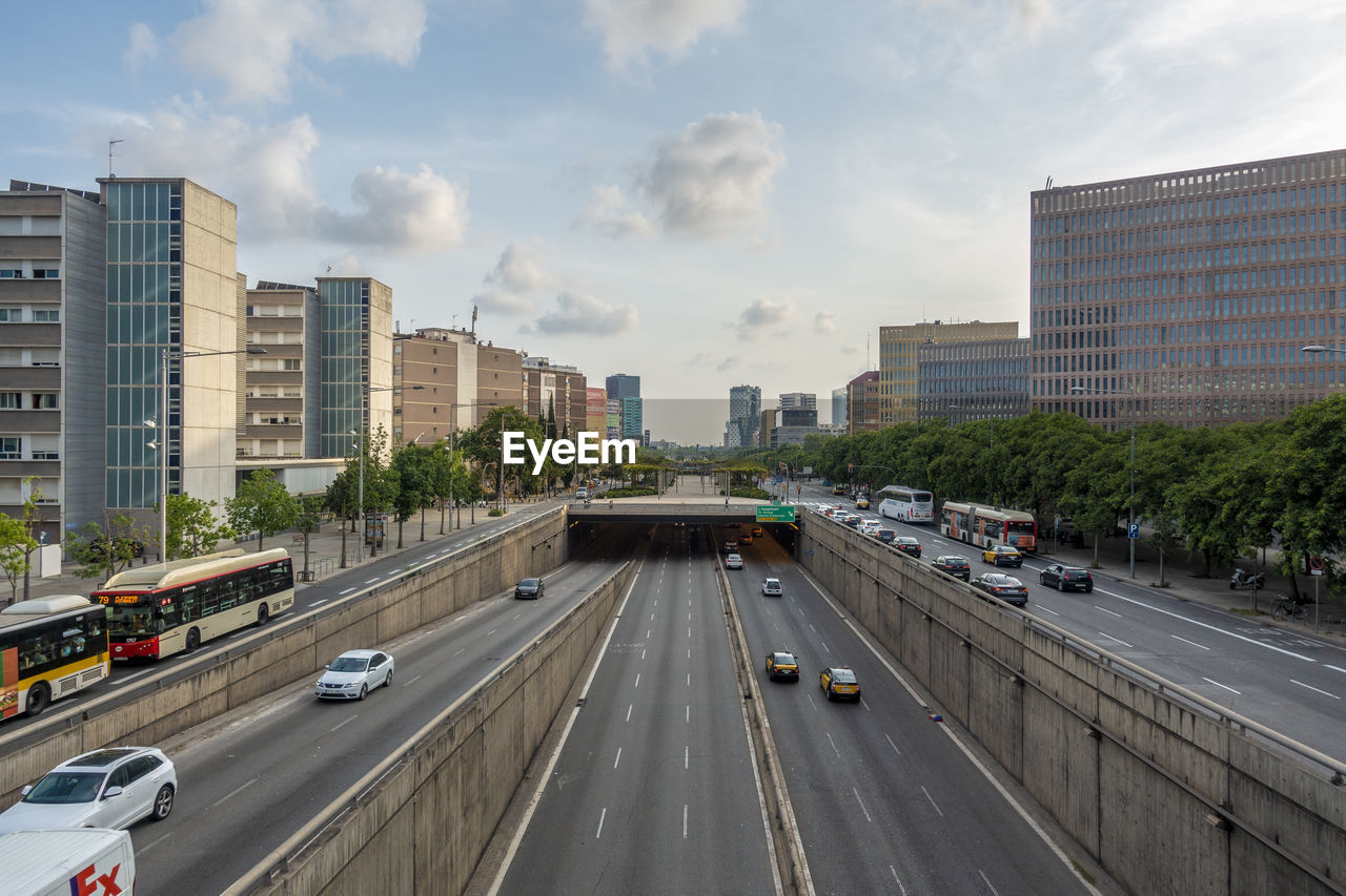 Vehicles on road in city against sky