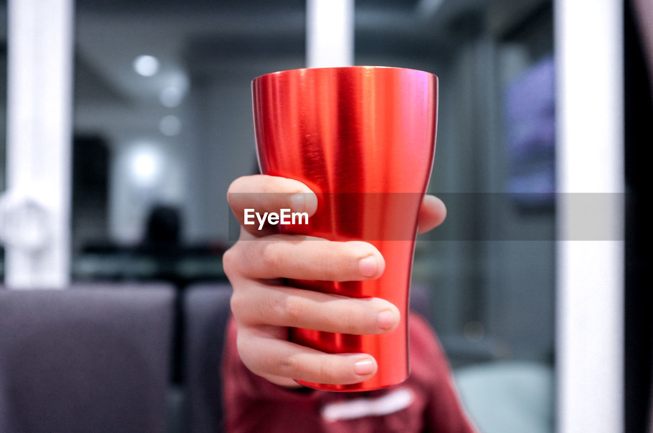 Close-up of woman holding red aluminum cup
