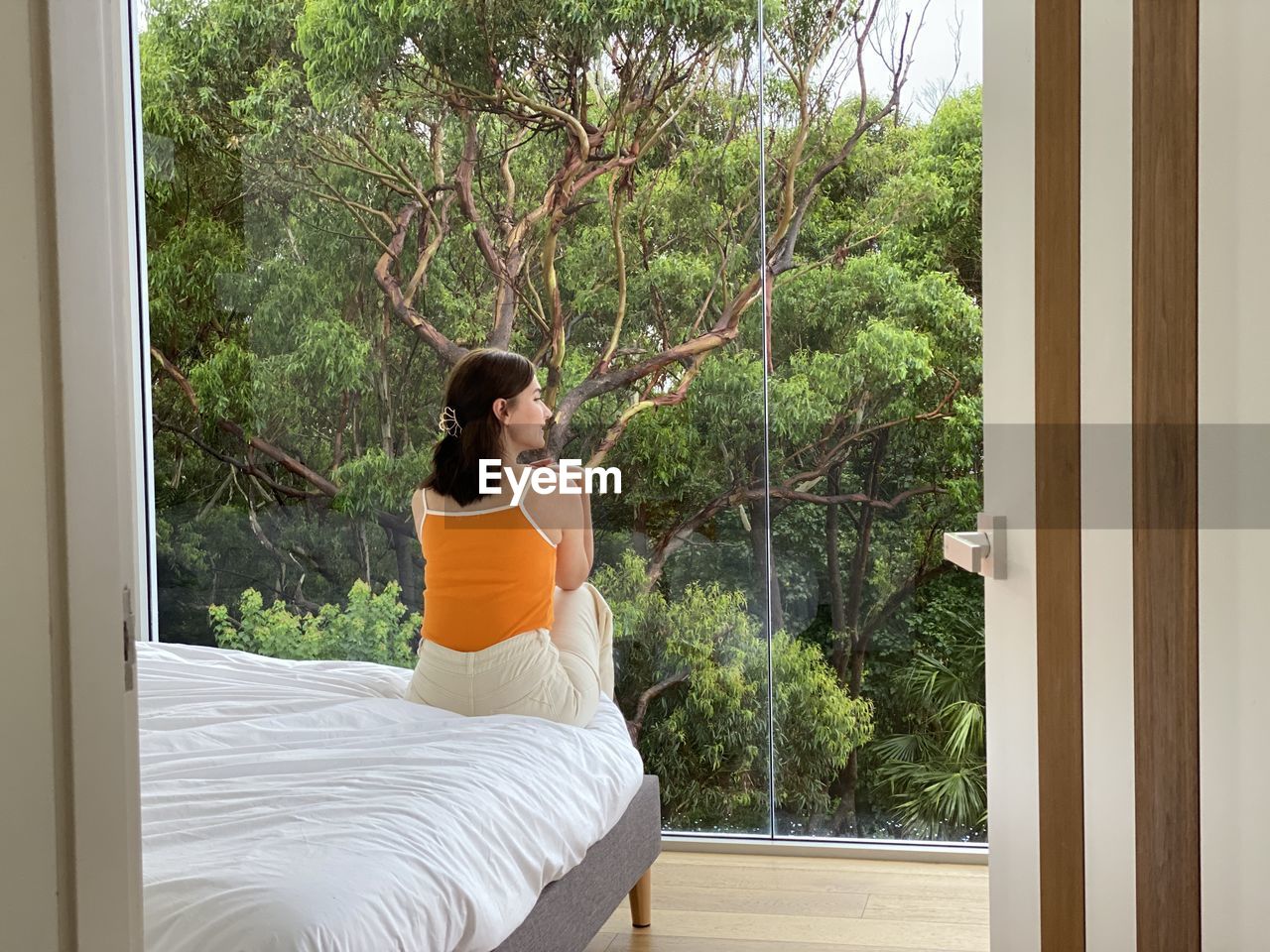 Rear view of woman sitting on bed at home