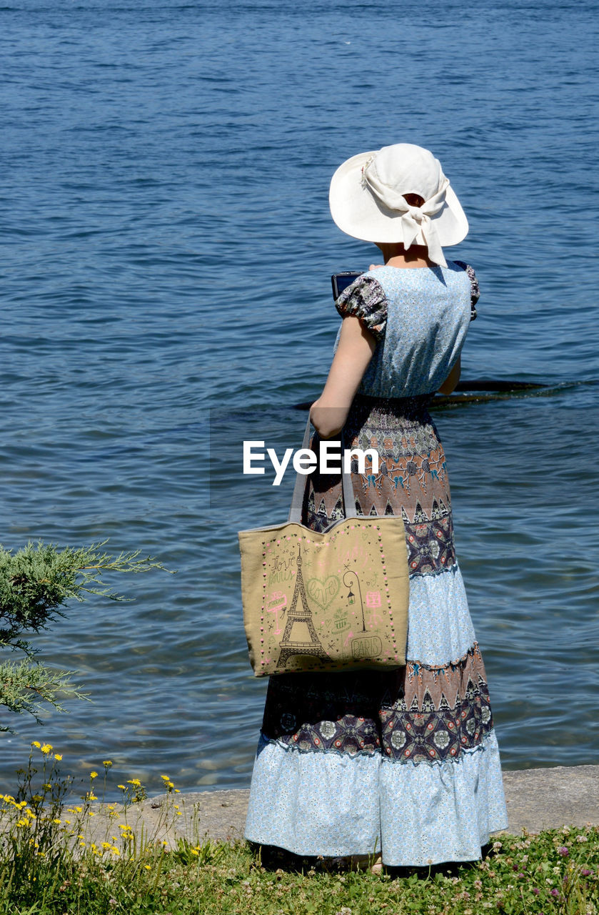 Rear view of woman standing by lake