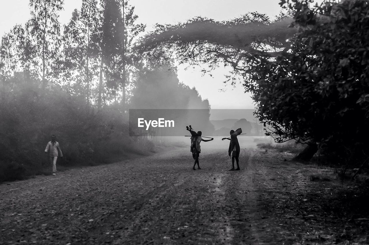 People standing on dirt road in foggy weather