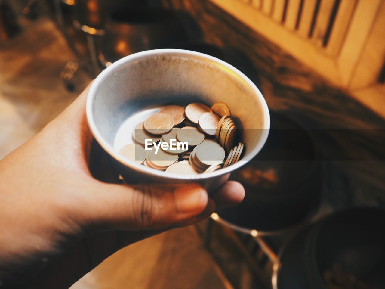 Cropped hand of person holding coins in container