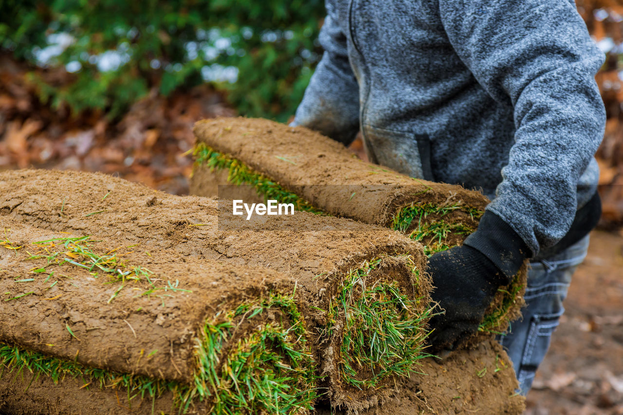 Low section of man stacking turf outdoors