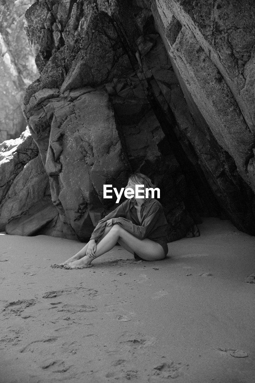 one person, full length, rock, black and white, monochrome photography, black, leisure activity, white, monochrome, lifestyles, land, relaxation, women, adult, sitting, nature, young adult, sand, day, person, casual clothing, clothing, resting, rock formation, outdoors, female, beach
