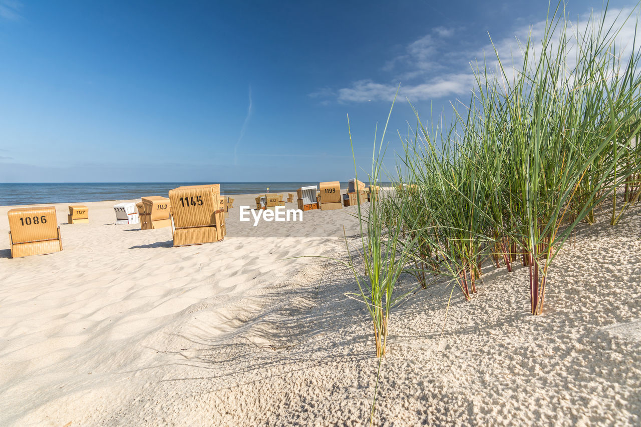 PANORAMIC VIEW OF HOODED BEACH CHAIRS ON SHORE AGAINST SKY