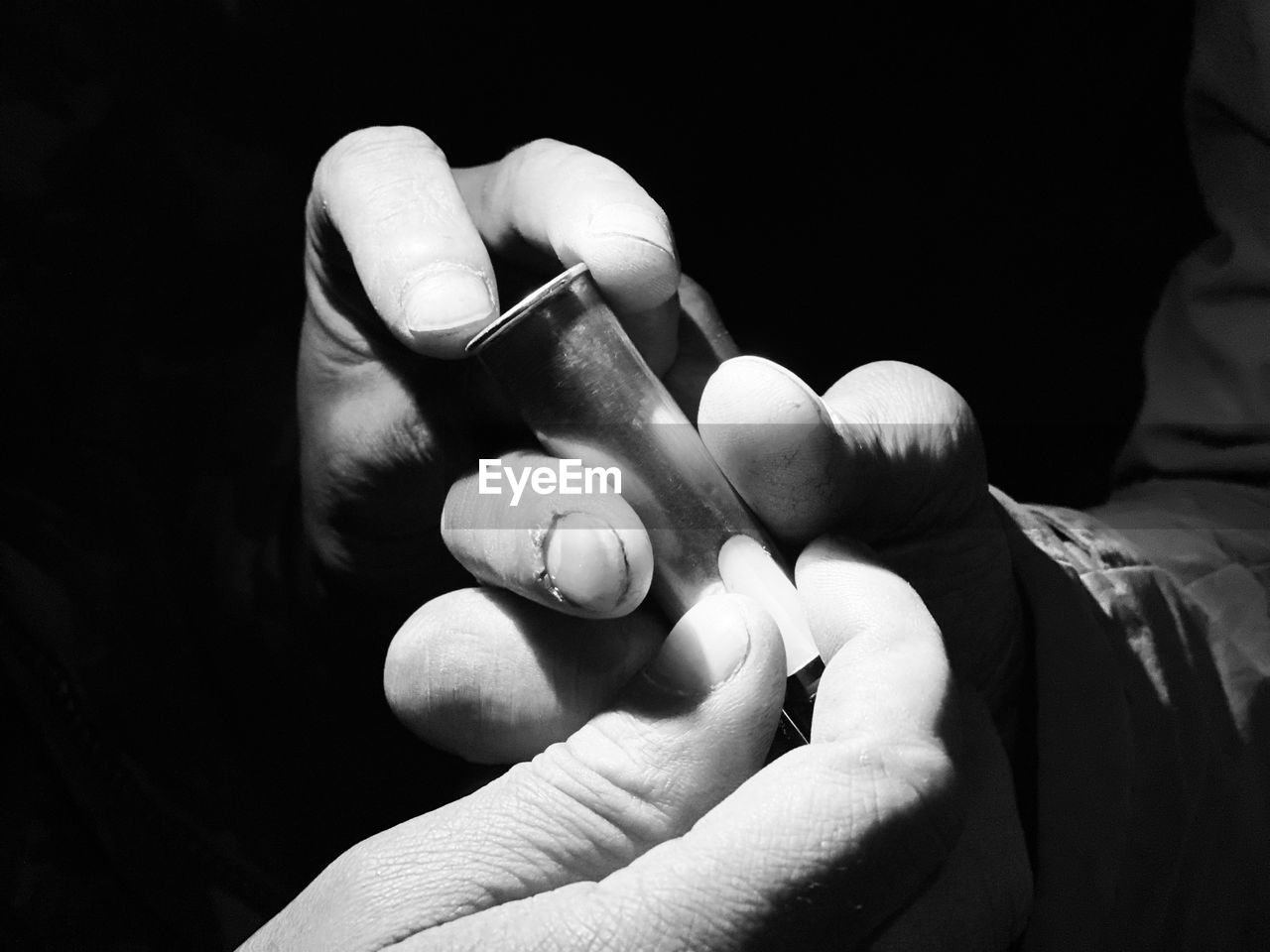 Close-up of hands holding electronic cigarette in darkroom