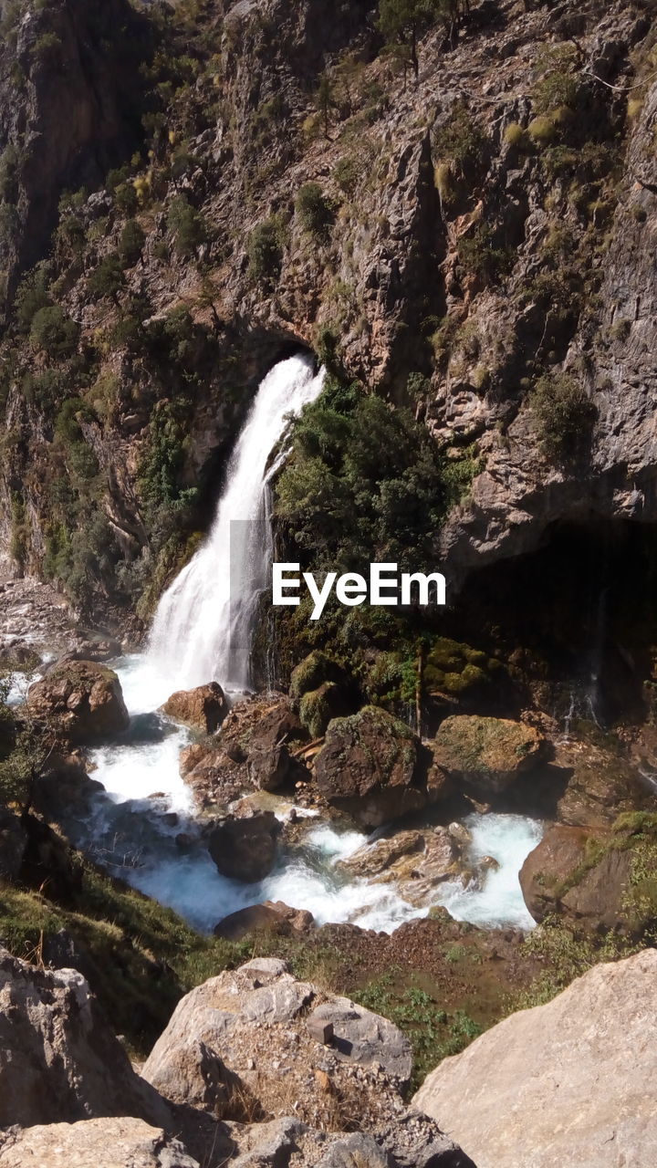 VIEW OF WATERFALL WITH ROCKS IN FOREGROUND