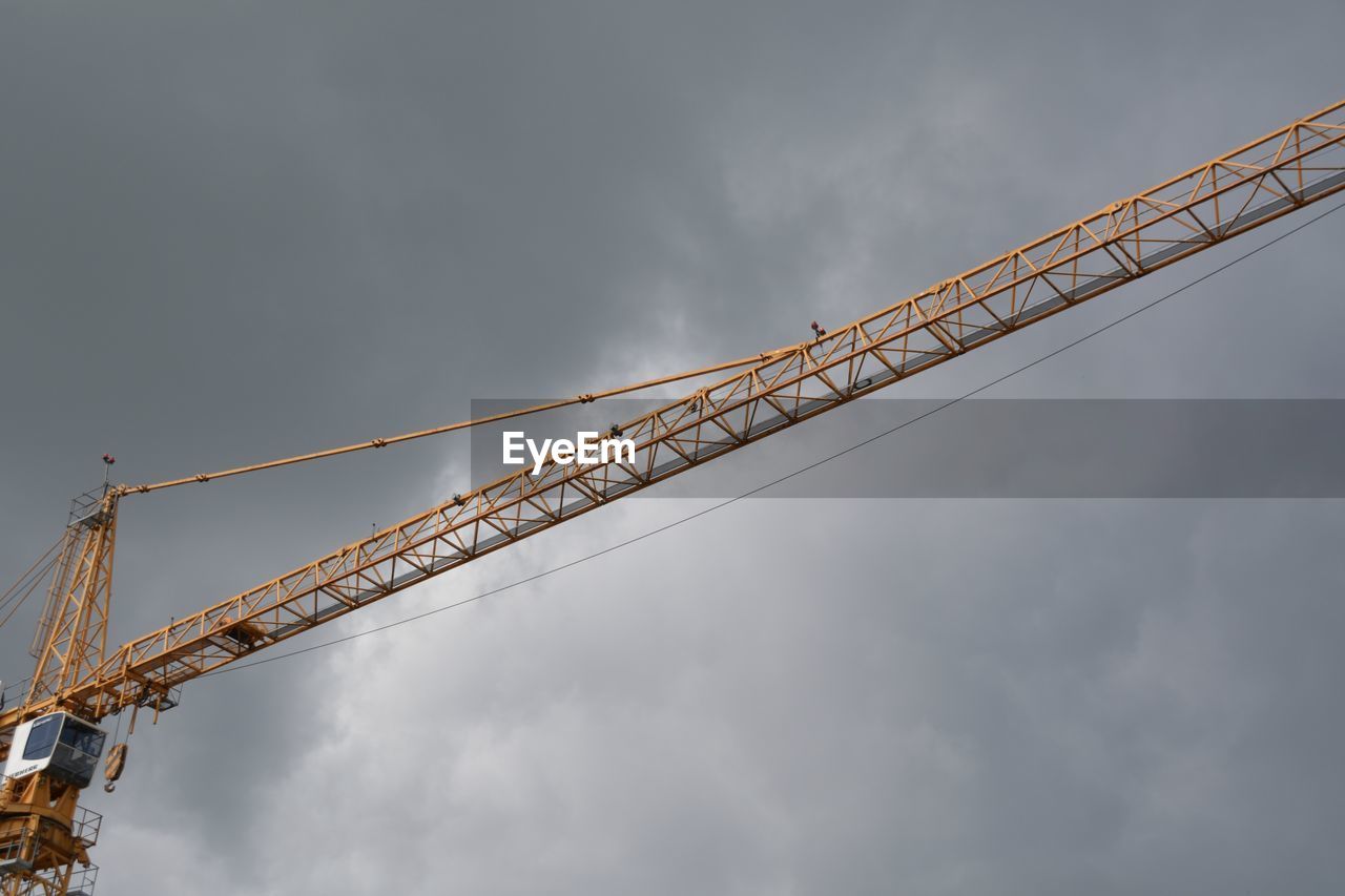 Low angle view of crane against cloudy sky