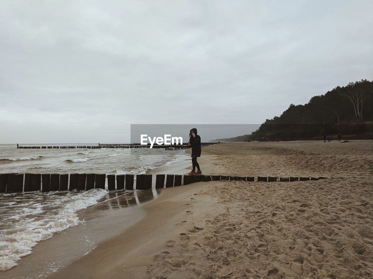 REAR VIEW OF WOMAN STANDING AT BEACH