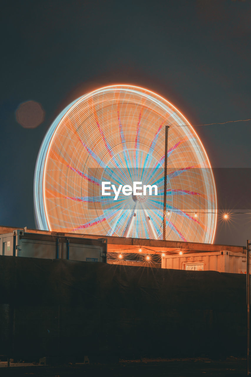 ILLUMINATED CAROUSEL AGAINST SKY AT NIGHT