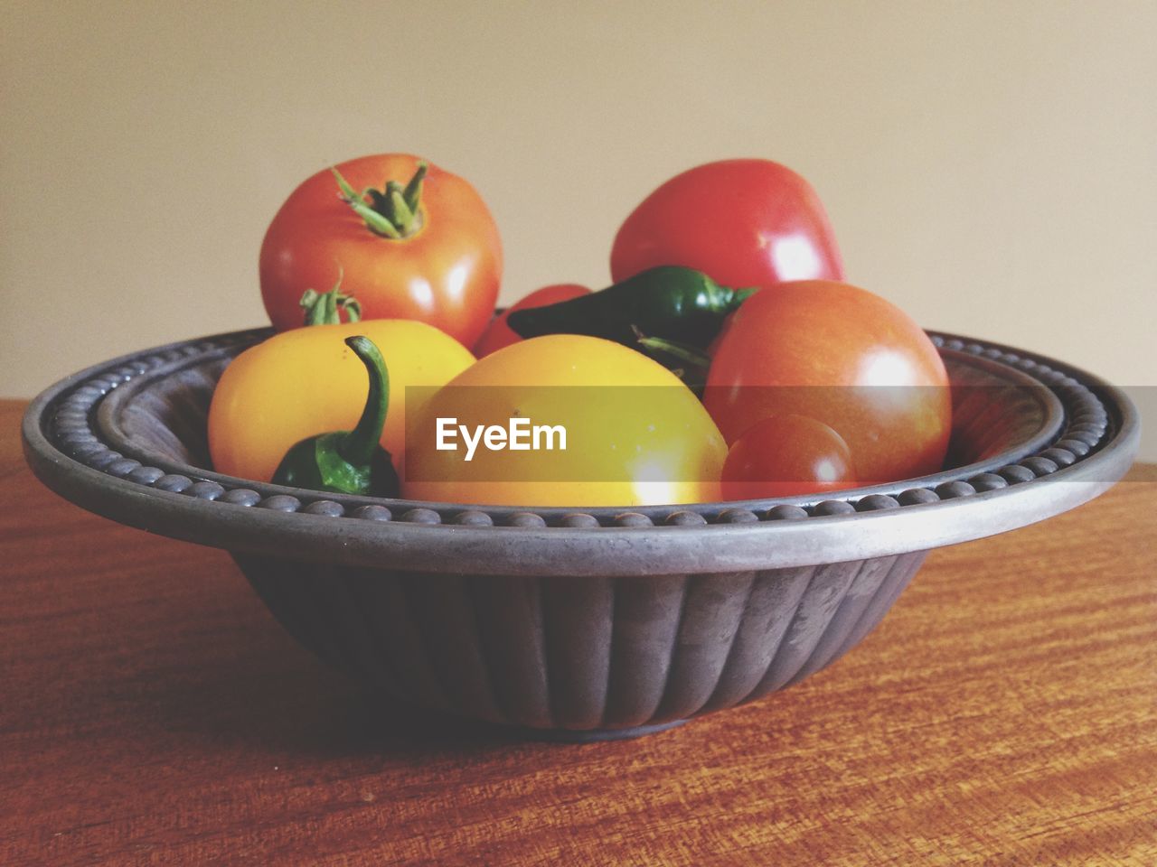 Tomatoes in container on wooden table