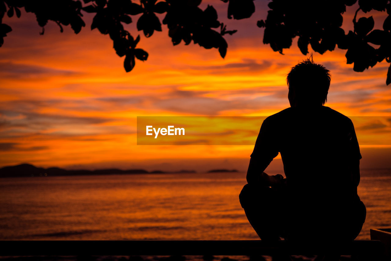 Rear view of silhouette man at beach during sunset