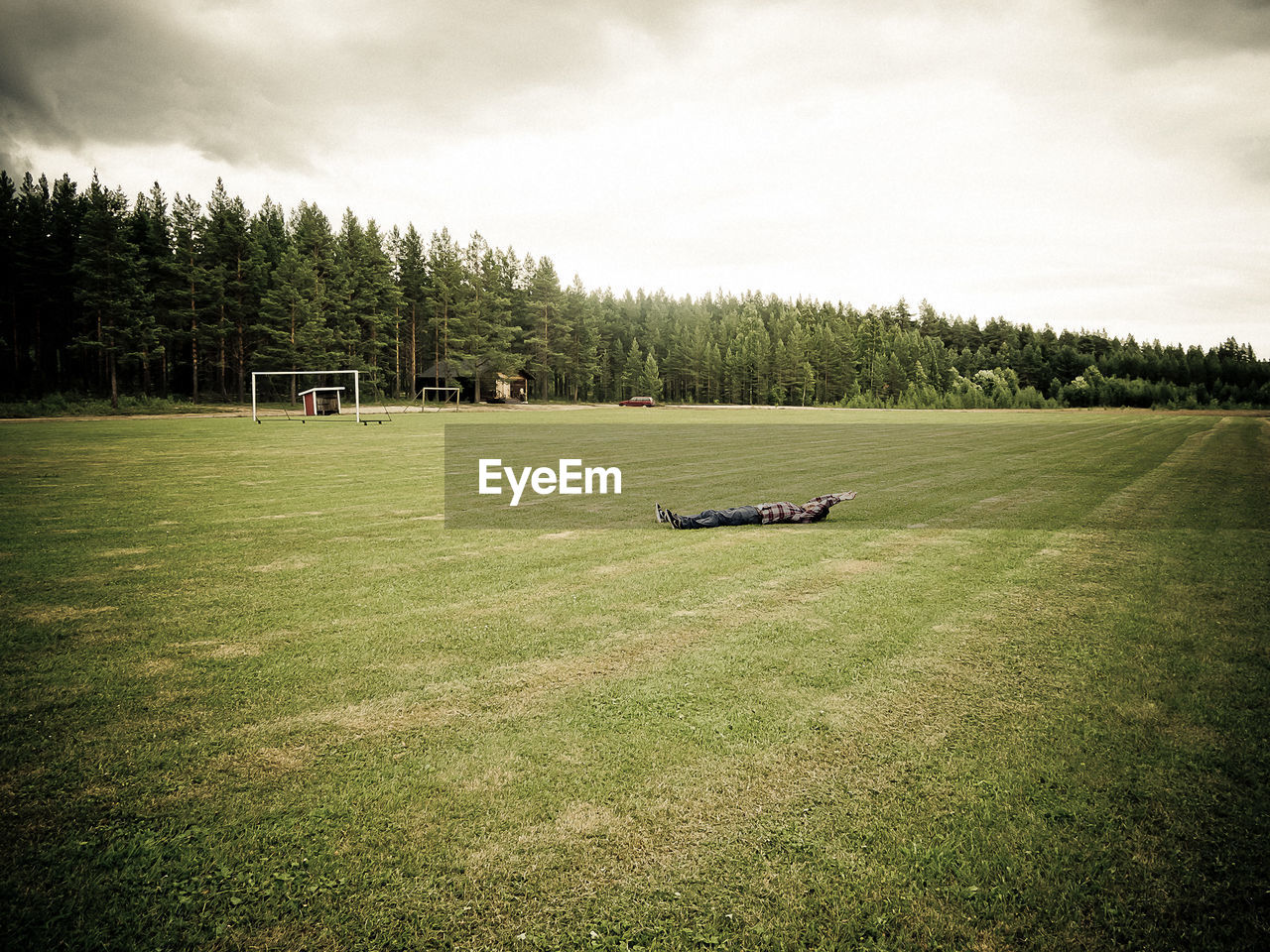 A person lying on a soccer flied in the woods