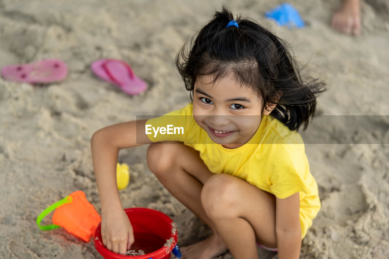 Portrait of cute girl playing on sand at beach