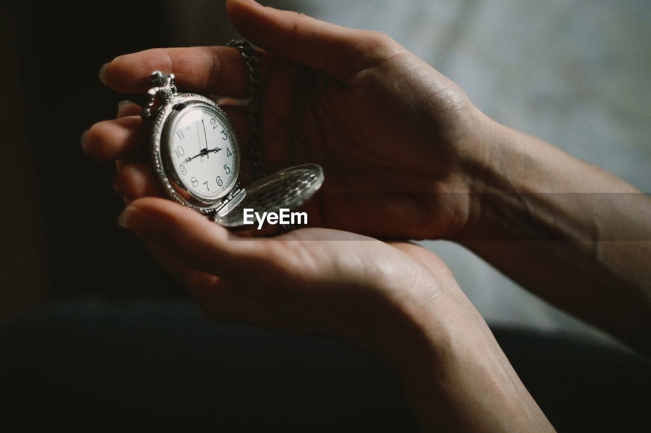 Cropped hand of person holding pocket watch