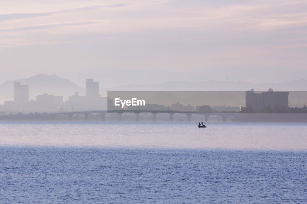 Distant view of people traveling in boat on sea during foggy weather