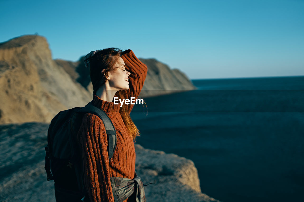 MAN LOOKING AT SEA AGAINST SKY