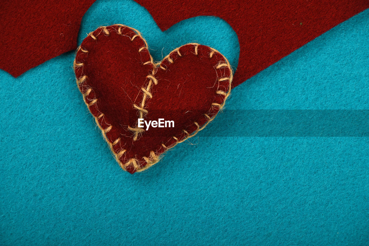 Close-up of felt craft heart over blue background