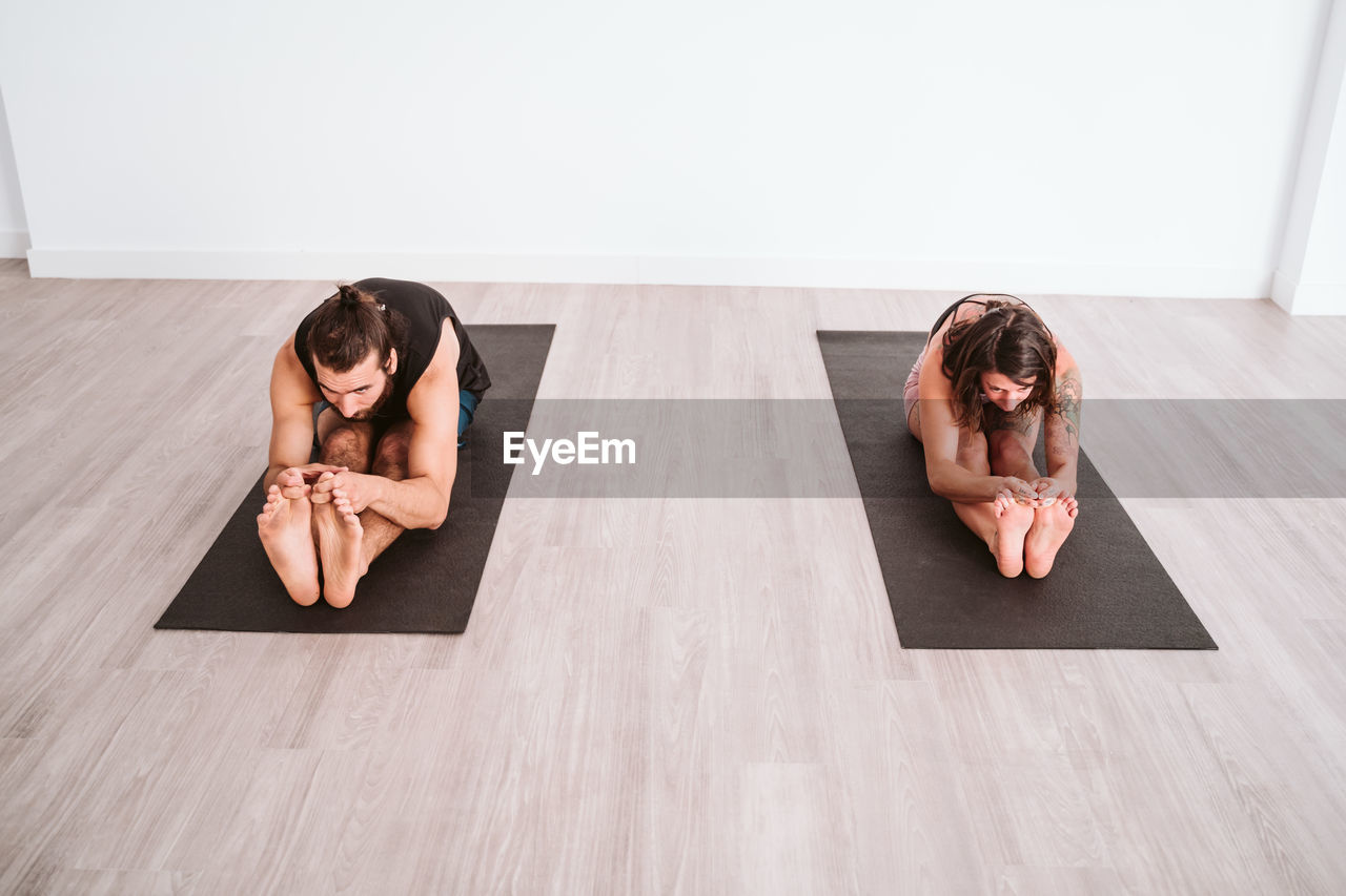 Man and woman doing yoga on floor 