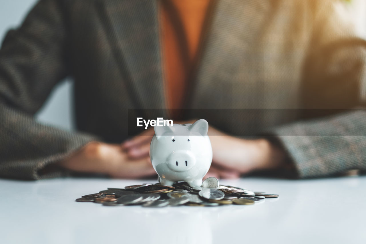 midsection of businessman putting coin in piggy bank