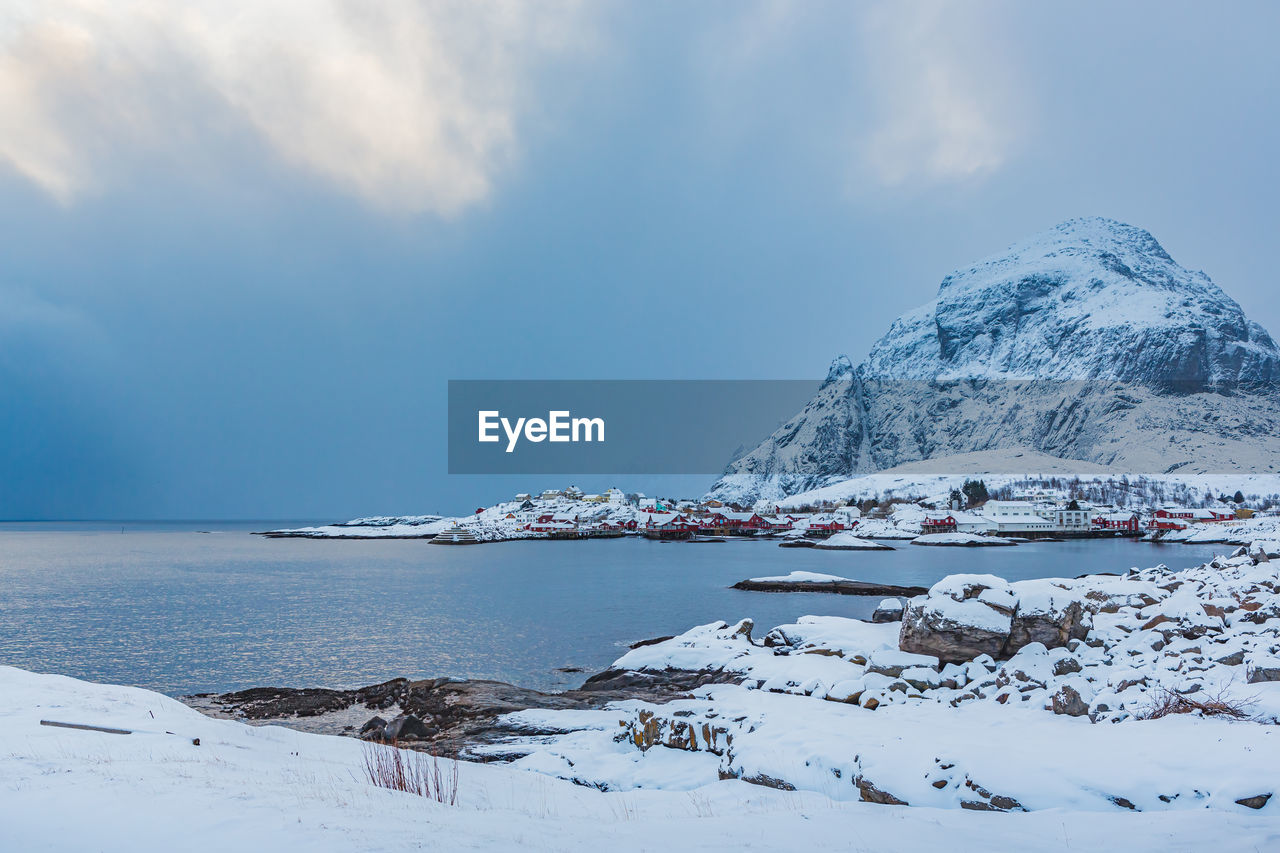 Scenic view of snow covered town by mountain against sky