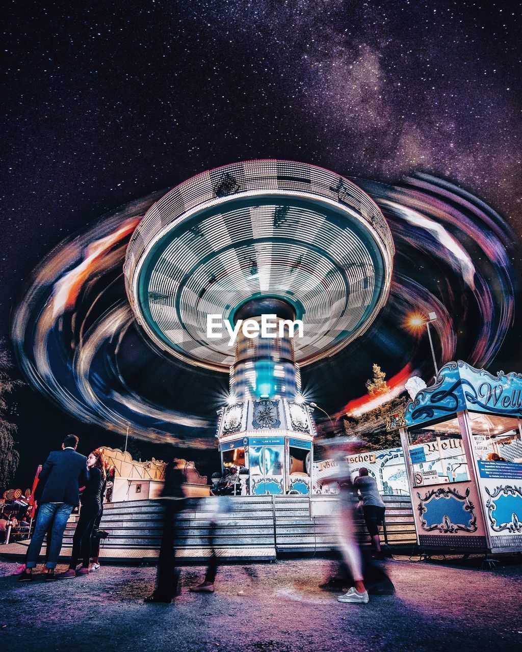 LOW ANGLE VIEW OF ILLUMINATED FERRIS WHEEL IN CITY AT NIGHT