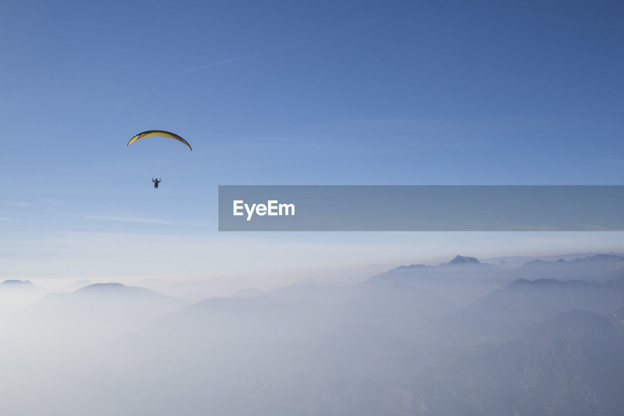 LOW ANGLE VIEW OF PEOPLE FLYING IN MOUNTAINS AGAINST SKY