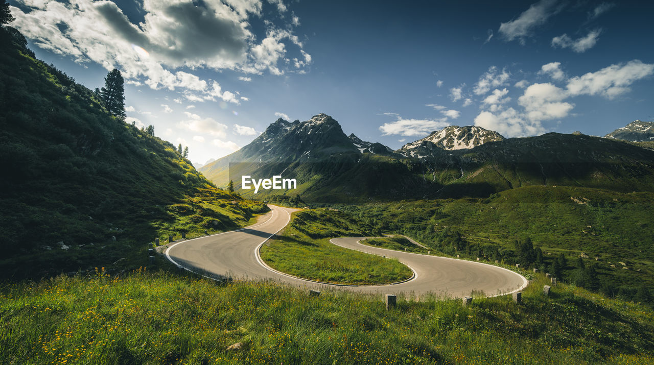 Scenic view of road by mountains against sky