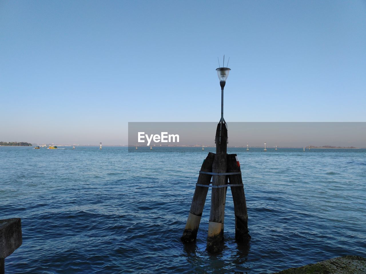 MAN ON WOODEN POST IN SEA AGAINST CLEAR SKY